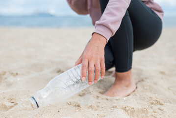 girl collects plastic bottles with garbage on the beach to save the cleanliness of the planet and ecology