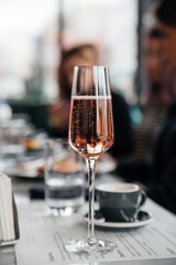 Glass of pink elegant champagne on table in restaurant