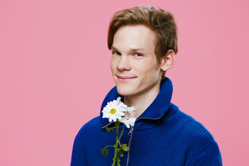 horizontal portrait of a cute, nice guy with a camomile in his hand