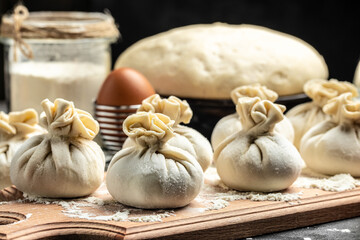 Raw Khinkali with meat, on a wooden board with flour, semi-finished products dumplings cooking khinkali. Georgian dumplings