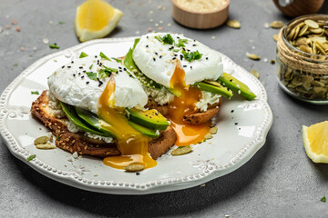 Healthy breakfast. Whole wheat toasted bread with avocado, poached egg, soft cheese and pumpkin seeds. Delicious breakfast or snack, Clean eating, dieting, vegan food concept. top view