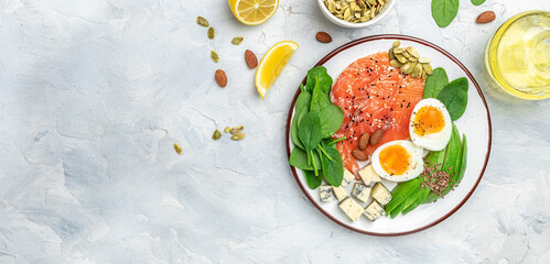 Keto diet food, salmon, avocado, cheese, egg, spinach and nuts. Ketogenic low carbs diet concept. Ingredients for healthy foods. Long banner format. top view