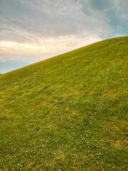 Idyllic Green Hill and Meadow Outdoor Summer Scene. Views of a fresh vivid green outdoor scene. Lush meadow of grass in the foreground. A large green hill stands tall in the background.