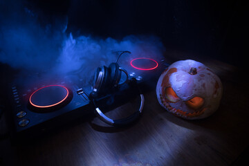 Halloween pumpkin on a dj table with headphones on dark background with copy space. Happy Halloween festival decorations