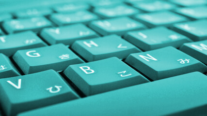 Japanese typing. Turquoise laptop keyboard closeup. Symbols on buttons of hiragana. Light teal tinted computer wallpaper or background. Electronic commerce in Japan. IT technology and data storage