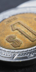 Coin of 1 Mexican peso close up. Peso of Mexico. News about economy or finance. Loan and credit. Wages and inflation. Focus on peso sign. Vertical illustration. Macro