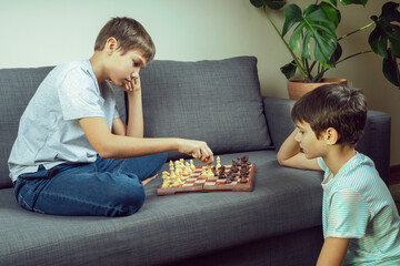 Two brothers are playing chess game. Strategic board game, leisure, entertainment at home