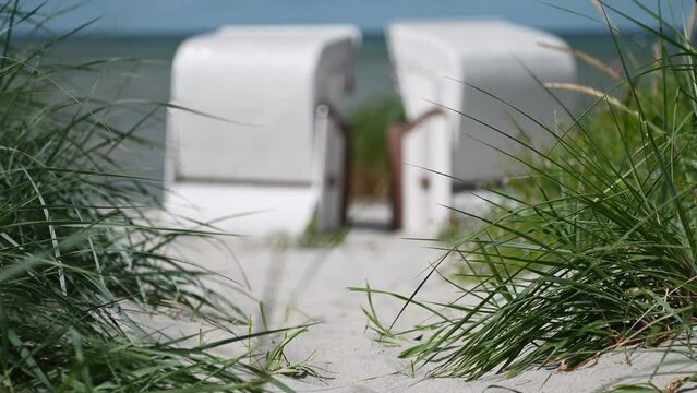4K slow motion video of white sand and dunes grass and beach chair or strandkorb in north Germany