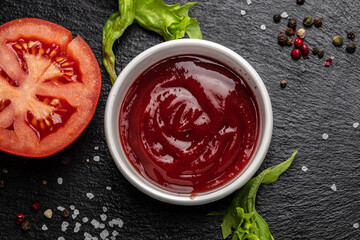 tomato sauce in bowl with fresh tomatoes on a dark background, place for text, top view