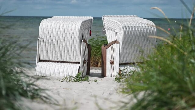 4K slow motion video of white sand and dunes grass and beach chair or strandkorb in north Germany