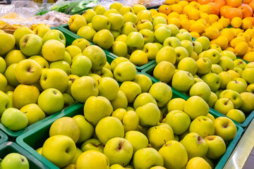 Pile of apples on the stall in the supermarket. Green apples in boxes on supermarket shelves