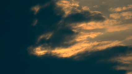 Background with dark clouds lit by the warm light of the setting sun.
