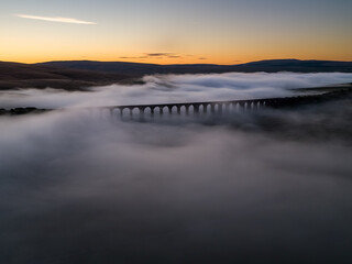 Drone view of the Iconic landmark Ribblehead Viaduct shrouded in early morning Mist