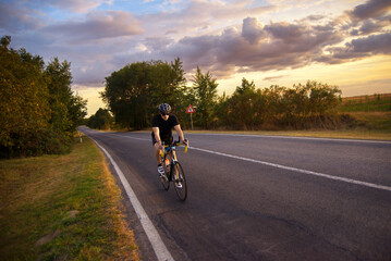 Young sports man cycling with bicycle on the road in summer