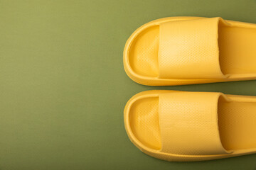 Stylish rubber yellow slippers on a green background.Changeable shoes.Beach shoes.Copy space. Place for text.