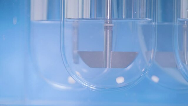 Experiments at the Lab. Sliding Shot of a Dissolution Apparatus Testing Medication Pills Dissolving Tablets in Liquid.Laboratory Routine.