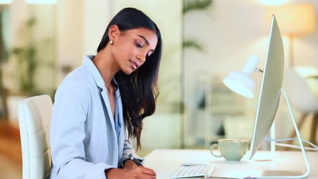 Businesswoman typing out financial reports while working on a computer in her office. Female accountant managing finances and doing bookkeeping using software to compile data and writing notes