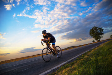Fototapeta premium Young sports man cycling with bicycle on the road in summer