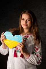 Portrait of a Ukrainian woman in a national costume with heart in hands
