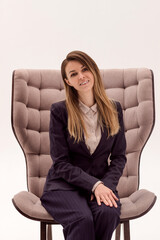 A young beautiful woman with long hair sits on a chair on a white background