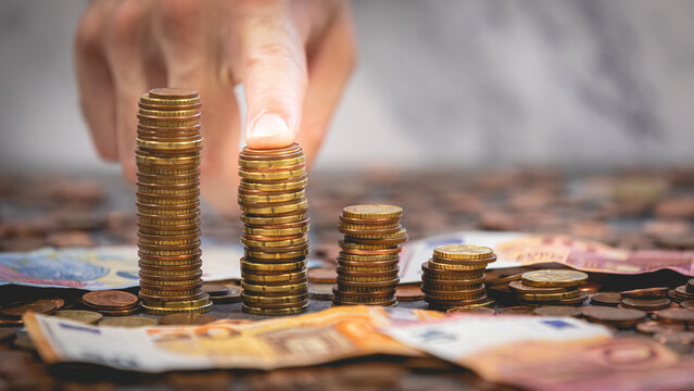 Une personne en train de pointer un tas d'argent avec des pi&egrave;ces et des billets, signifiant le pouvoir d'achat et l'inflation.