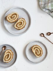 Pieces of biscuit roll with apple jam on a plates. Checkered kitchen White background, flat lay