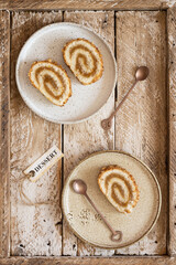 Pieces of biscuit roll with apple jam on a plates. Wooden tray, copper color teaspoons. Flat lay