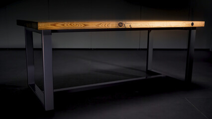 Wooden table on black background. Stock footage. Close up of wooden table with black iron legs standing in the empty room in the dark that changes by the light.