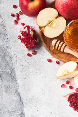 Rosh Hashanah. Pomegranate, apples and honey traditional products for celebration on rustic grey background. Jewish Autumn Rosh Hashana celebration. Jewish holiday Rosh Hashana design. Selective focus