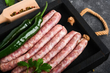 Raw sausages. Bratwurst or sausages with ingredients on cutting board with spices on a stone...