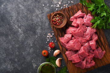 Raw chopped beef meat. Raw organic meat beef or lamb, spices, herbs on old wooden board on dark...
