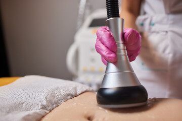 Rf skin tightening, belly. Hand of cosmetician, female body. Non surgical body sculpting.