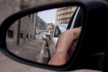 a car side mirror reflecting a human arm from the window