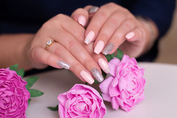 Obraz na płótnie Canvas Close up view of beautiful female hands with romantic manicure nails, pink gel polish, peonies flowers