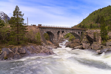Obraz premium The Stuguflåt Bridge (Norwegian: Stuguflåtbrua or Stuguflåten bru), a stone railway bridge on the Rauma Line over the Rauma River in Innlandet county, Norway.