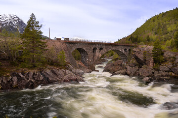 Fototapeta na wymiar The Stuguflåt Bridge (Norwegian: Stuguflåtbrua or Stuguflåten bru), a stone railway bridge on the Rauma Line over the Rauma River in Innlandet county, Norway.