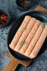 Raw homemade sausages (chicken, turkey) in a pan on a dark background with spices