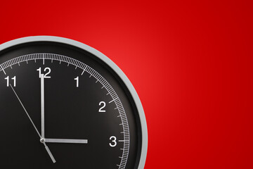 Wall clock showing three o'clock on red background. Copy space