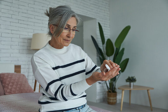 Senior woman taking medicines while sitting on the bed at home