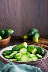 Ripe sliced cucumbers on a plate on the table. Organic diet food. Vertical view