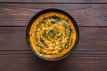 Tasty autumn soup, top view. Pumpkin carrot curry soup on brown background, top view. 