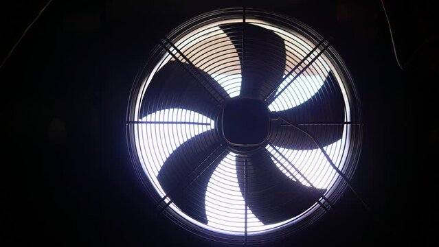 Large production fan for ventilation of the room. Tearing and stopping the fan on a black background with a lumen between the lop.