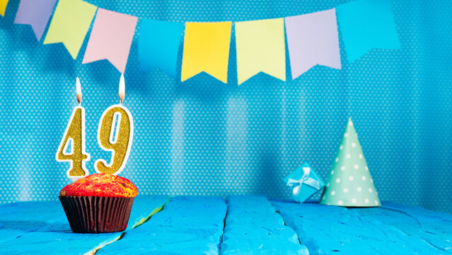 Happy birthday card with a muffin decorated with a festive cake and burning candles. Copy space. Beautiful background happy birthday on the background of blue boards with a number of candles number 49