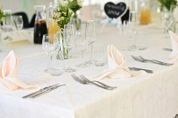 Table at a luxury wedding reception. Beautiful flowers on the table. Serving dishes, glass glasses, waiters work