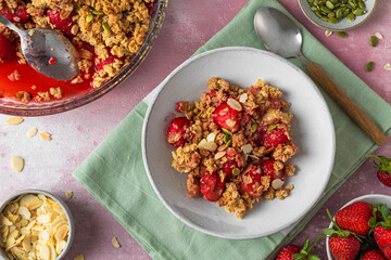Strawberry crumble with almonds in a plate with spoon on pink background. Top view. tasty breakfast
