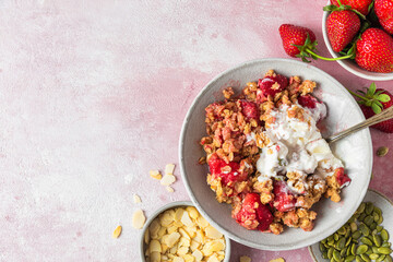 Strawberry crumble with ice cream and almonds in a plate with spoon on pink background. Top view...