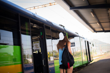 A young athletic woman stands near the train at the railway station.