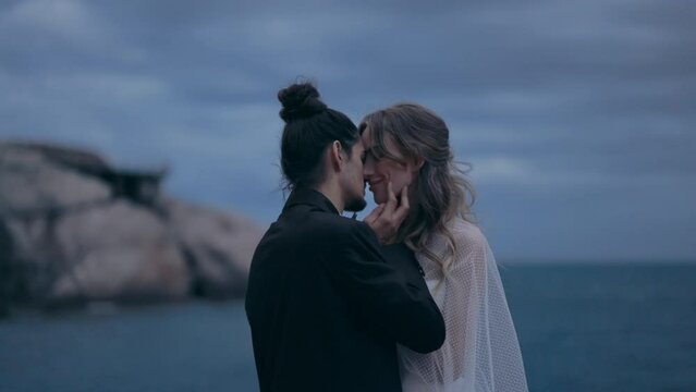 Young Couple. Man Adjusts Girls Hair. Sea And Mountains In Background. Tender Hugs Of Lovers.
