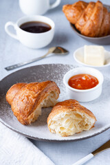 A freshly baked French Croissant, coffee, butter and jam