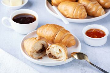 A freshly baked French Croissant, coffee, butter and jam